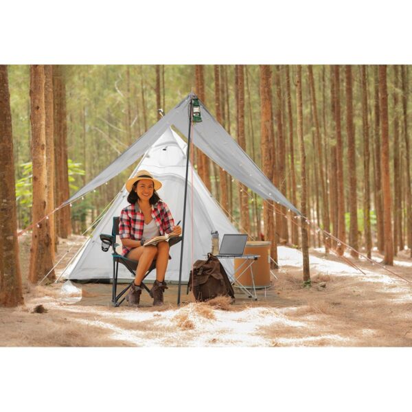Young woman tourist sitting near the tent and reading a book. pe Young woman tourist sitting near the tent and reading a book. pe
