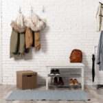 Stylish hallway interior with shoe rack and hanging clothes on b