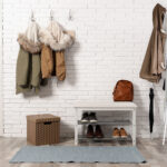 Stylish hallway interior with shoe rack and hanging clothes on b