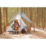 Young woman tourist sitting near the tent and reading a book. pe