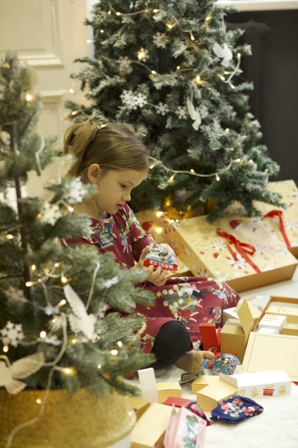 adventes-kalendars-merry-christmas-4 Meitene apskata pārsteigumu no adventes kalendāra pie eglītes